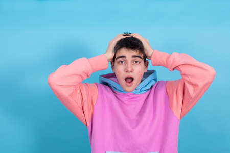 isolated portrait of young teenage boy with surprise or admiration expression in color backgroundの写真素材
