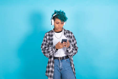 young brunette girl with mobile phone and headphones isolated on backgroundの写真素材