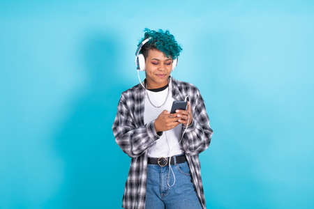 young brunette girl with mobile phone and headphones isolated on backgroundの写真素材