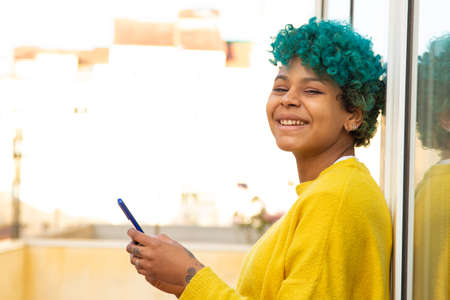 young african american girl with mobile phone outdoors on the terrace of the apartment