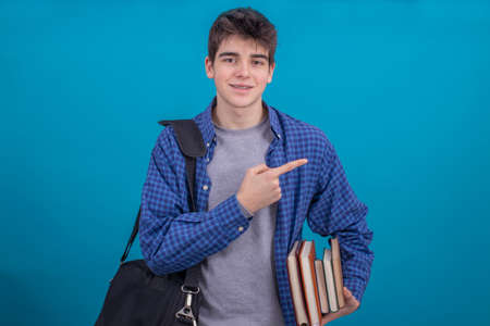 young teenage student with books and backpack isolated on blue backgroundの写真素材