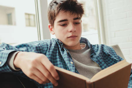 young teenage boy reading or studying at homeの写真素材