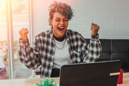 young woman or girl with computer and expression of success or celebration at home or in the officeの写真素材