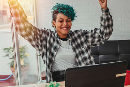 young woman or girl with computer and expression of success or celebration at home or in the office