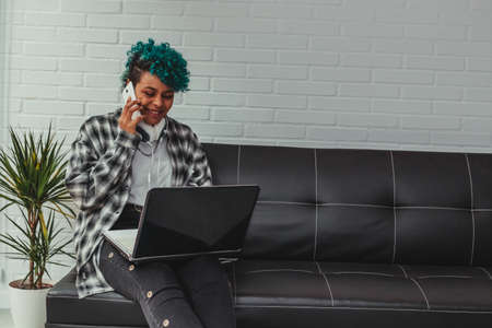 young african american girl with computer and mobile phone on the sofa sitting