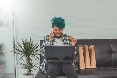 young girl with computer and credit card with shopping bags at homeの写真素材