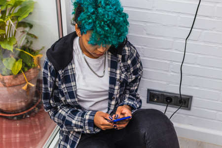 young woman with smartphone in the apartment next to the windowの写真素材