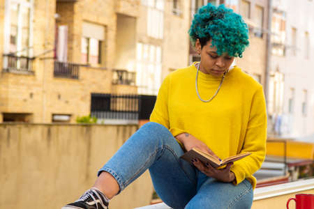 young girl reading the book outdoors in the cityの写真素材