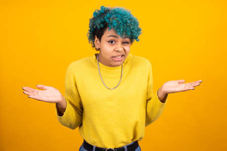 fashionable african american girl or woman with blue hair isolated on yellow backgroundの写真素材