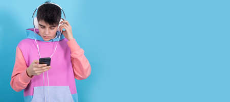 teenager or student with mobile phone and headphones isolated on color background