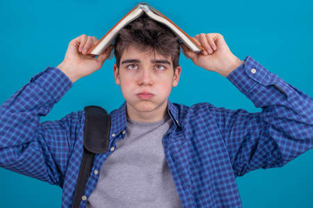 isolated young student or teenager with books on head and expression of tired or stress