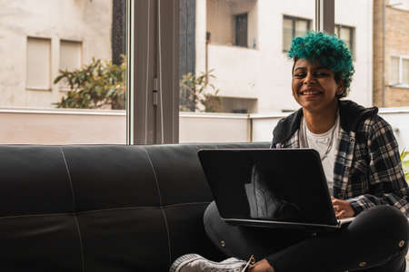 young woman or girl with laptop at home or apartmentの写真素材
