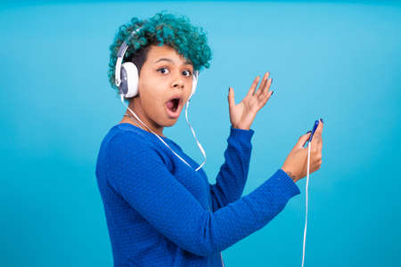girl with mobile phone and headphones isolated on color background