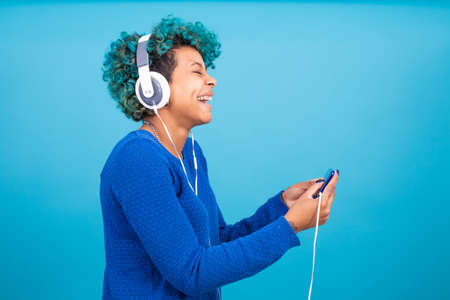 girl with mobile phone and headphones isolated on color background