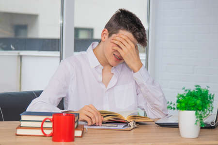 teenage student at the desk with tired or headache expression