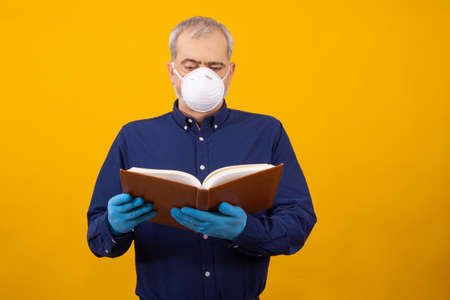 isolated adult or senior man with book, gloves and mask