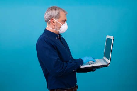 man with mask and gloves working with laptop isolated on backgroundの写真素材