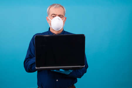 adult or senior man with face mask and laptop isolated on color backgroundの写真素材