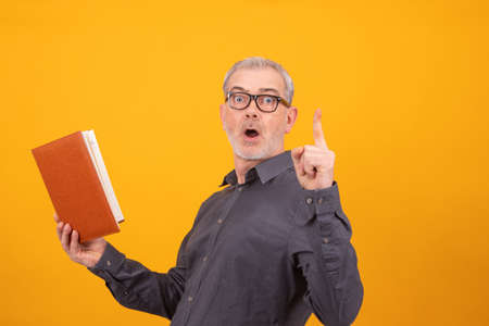 adult man with book or agenda and glasses with finger up pointing or warningの写真素材