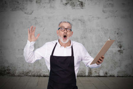 businessman with shopkeeper uniform surprised isolated on backgroundの写真素材