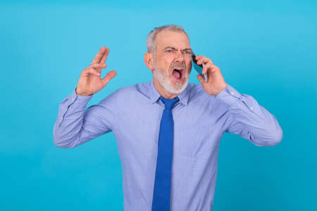 furious businessman talking on mobile phone isolated on backgroundの写真素材