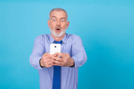shocked businessman looking at mobile phoneの写真素材