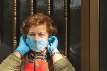 senior woman with gloves and mask protected from contagion at the doorの写真素材