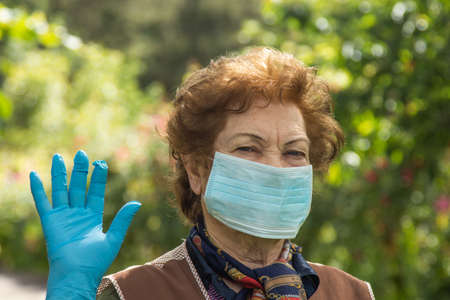 portrait of senior woman with mask and gloves protected from contagionの写真素材