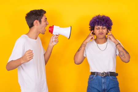 couple with megaphone yelling the man to the woman covering her earsの写真素材