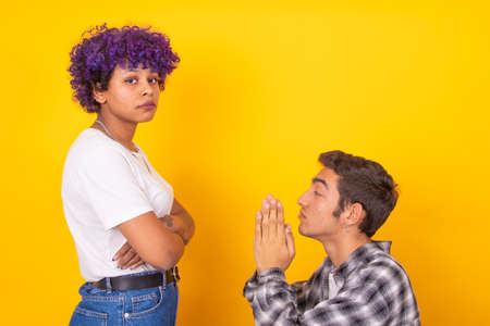 young man and woman couple asking for forgiveness isolated on background