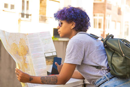 young african american girl with map and backpack with sunglasses in the city outdoors