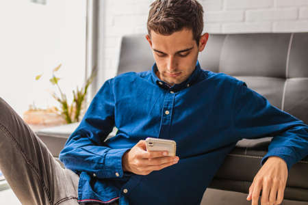 portrait of young man with mobile phone at home