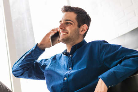 portrait of young man with mobile phone at home