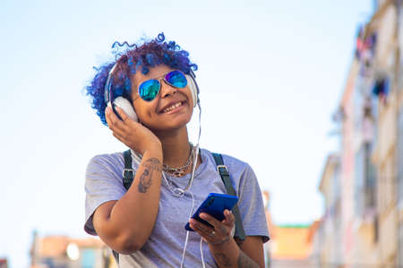 urban young girl with smartphone and headphones listening to music outdoors in the cityの写真素材