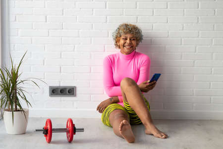 athlete woman with mobile phone sitting at home or gymの写真素材