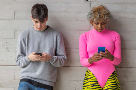 multiethnic young couple with mobile phone on the streetの写真素材