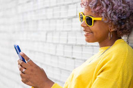 afro american girl with mobile phone in the street and sunglasses