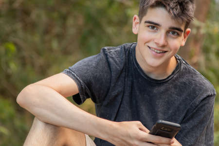 young male teenager with mobile phone outdoorsの写真素材