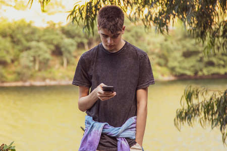 young male teenager with mobile phone outdoors
