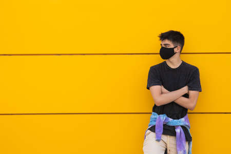 young male teenager on street wall with face maskの写真素材