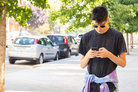 young man with mobile phone walking in the cityの写真素材