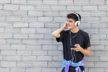 young male with mobile phone and headphones on the streetの写真素材