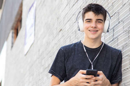 young man on the street with mobile phone and headphones