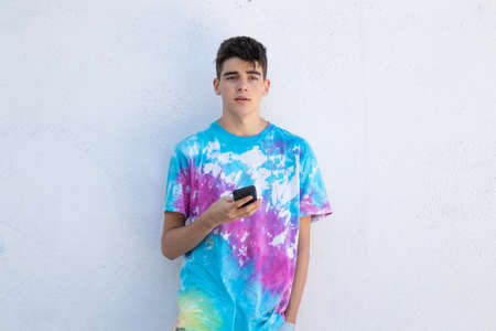 young teenager boy with mobile phone on white street wallの写真素材