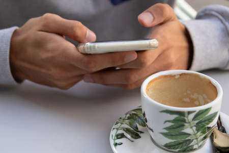 closeup of hands with mobile phone and coffee cup