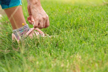 hands of athlete woman tying shoe in fieldの写真素材