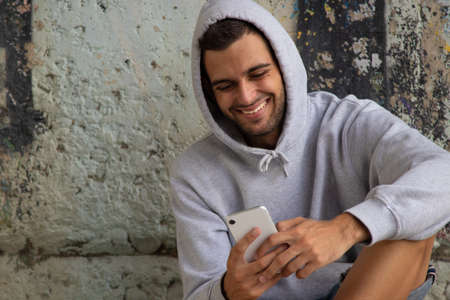 young man sitting on the street floor with mobile phoneの写真素材