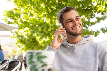 young man in cafe terrace with mobile phone