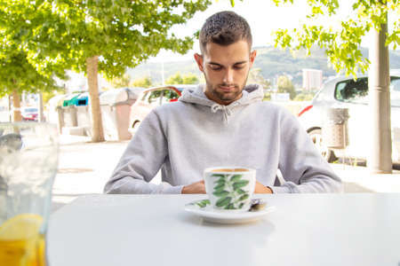 young man in cafe terrace with mobile phone