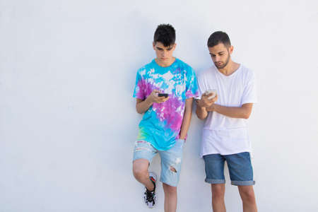 young teenagers with mobile phone on the street wallの写真素材